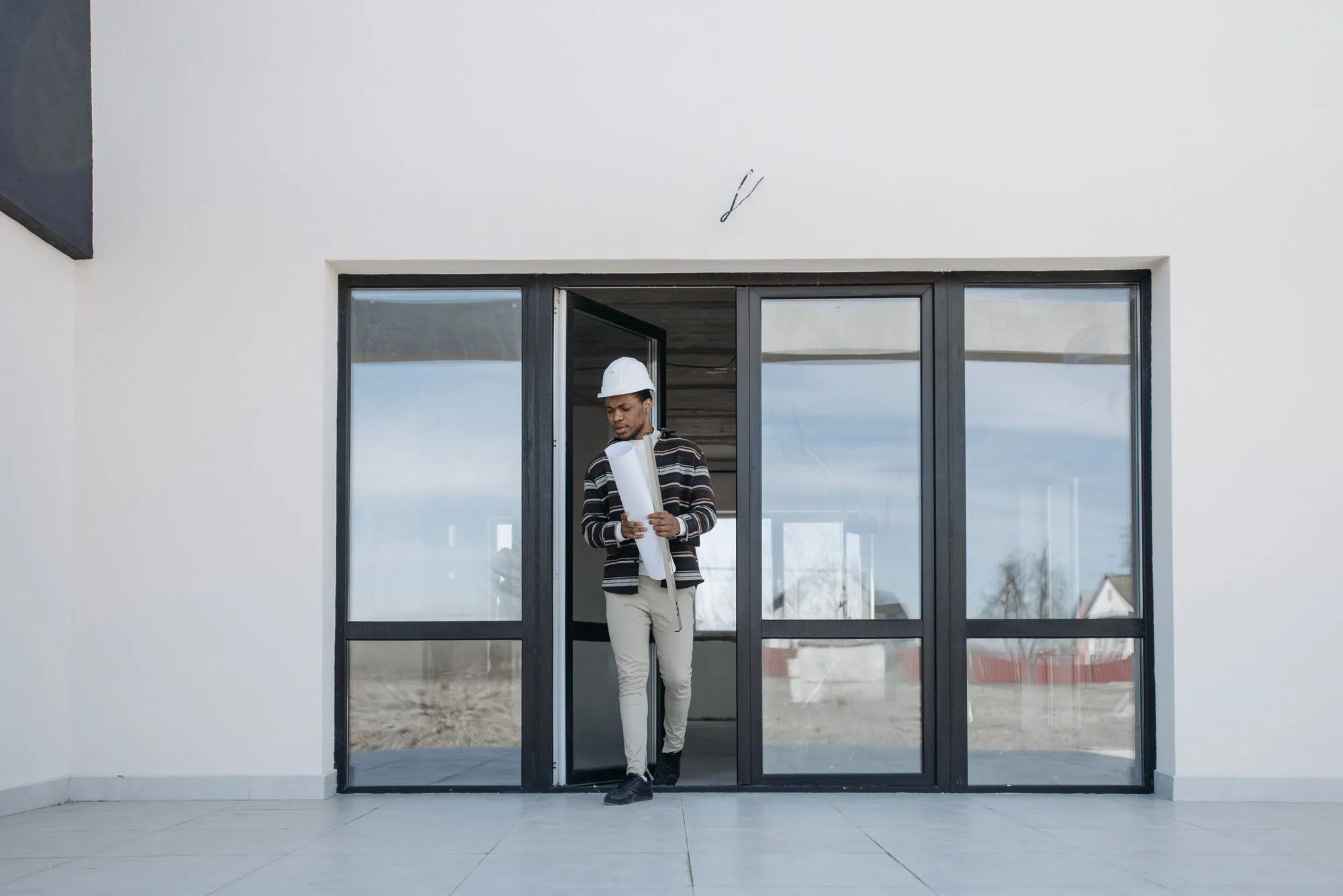 Contractor at a new aluminum-and-glass storefront entry inside a renovated commercial space
