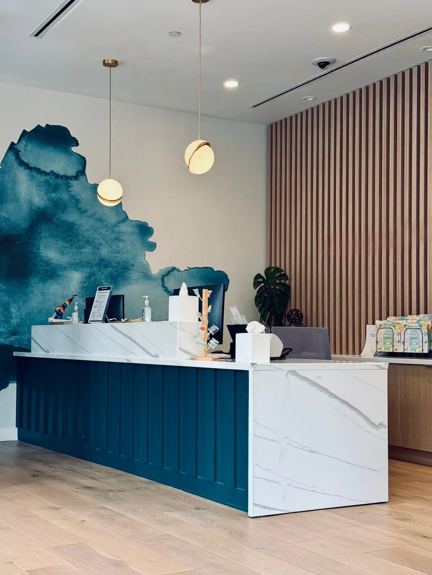 Finished clinic reception desk with stone-look counter, navy wainscot and wood slat wall