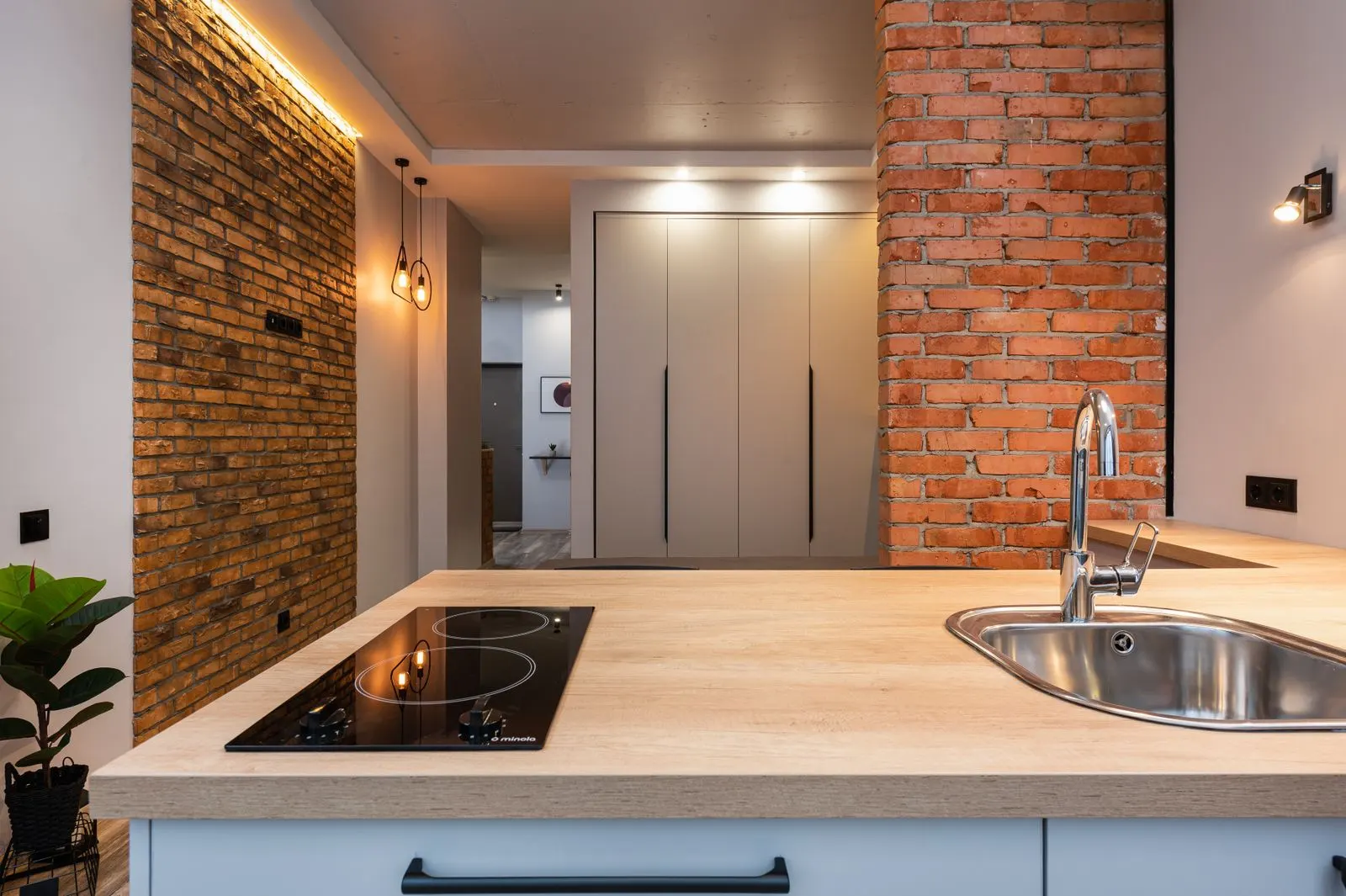 Renovated apartment kitchen with exposed brick, oak countertop and pendant lighting